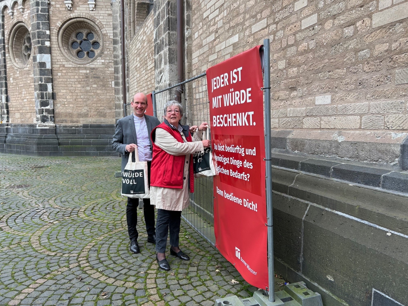 Münsterkaplan Dr. Christian Jasper und Birgit Gaschina-Hergarten – ehrenamtliche Mitarbeiterin – am „Ort voller Würde“ vor der Münsterbasilika.