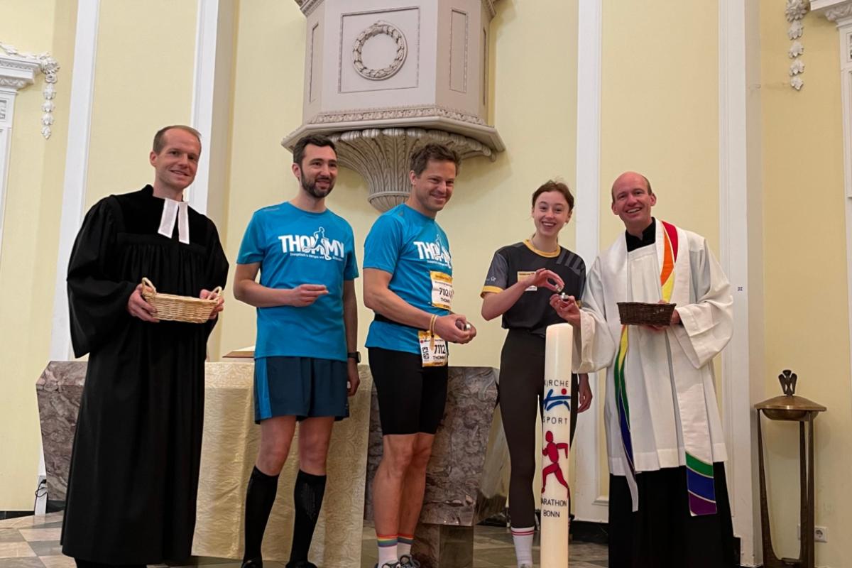 Vikar Wisssing (l.), Kaplan Dr. Christian Jasper (r.) und weitere Teilnehmende des Marathons entzündeten die Marathonkerze in der Schlosskirche.